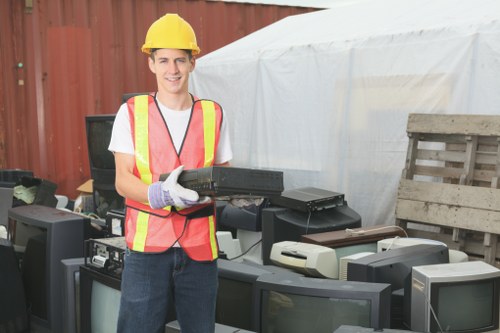 Business staff segregating recyclables in labelled containers for sustainable rubbish area